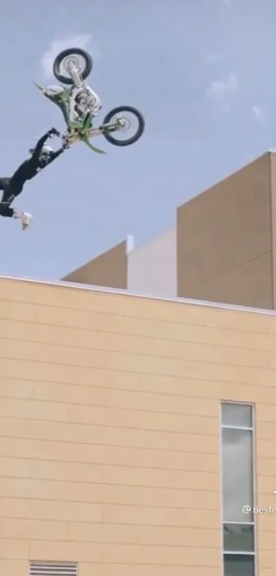 Motorcycle performing a high-flying stunt over a beige urban building.