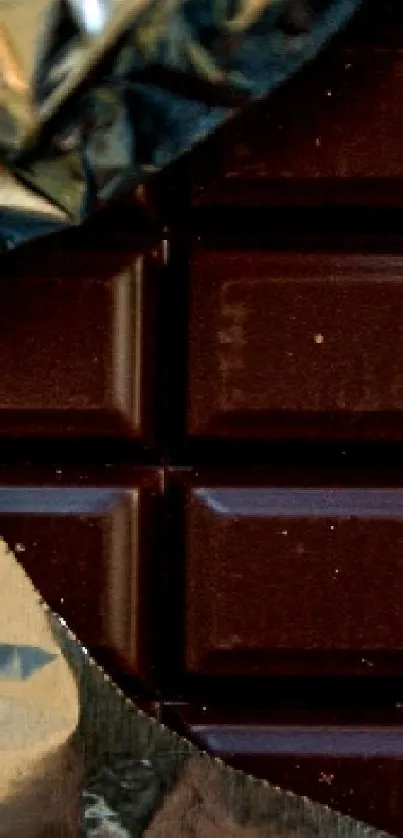 Dark chocolate bar partially wrapped in foil, perfect for a wallpaper.
