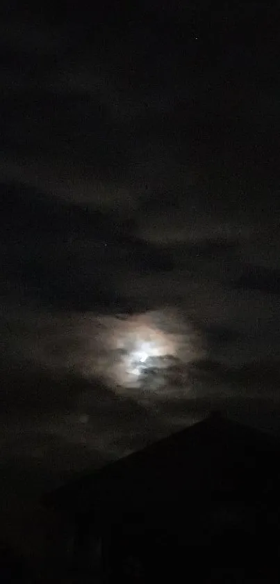 Dark night sky with clouds and moon shining through.