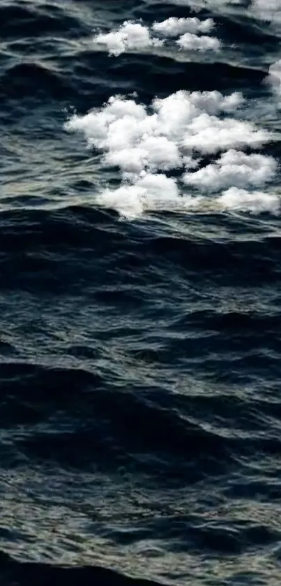 Dark ocean waves with white clouds above.