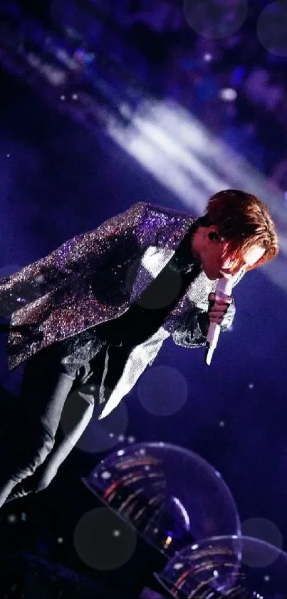 A performer in a glittery jacket on stage with colorful lights.