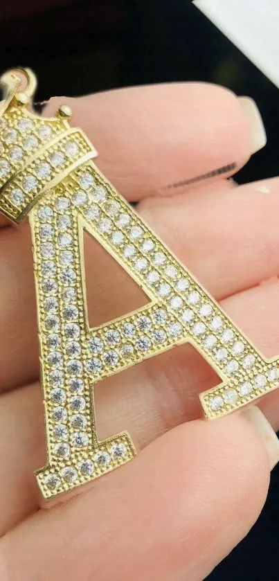 Gold letter A pendant with diamonds on a hand showcasing luxury.