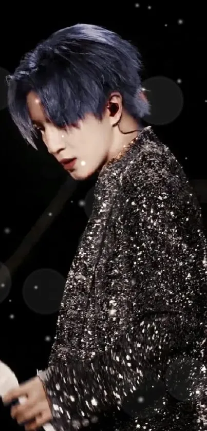 Performer with blue hair in sparkling black on stage.