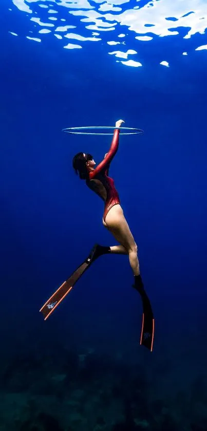 Diver in a red suit swimming through deep blue ocean waters.