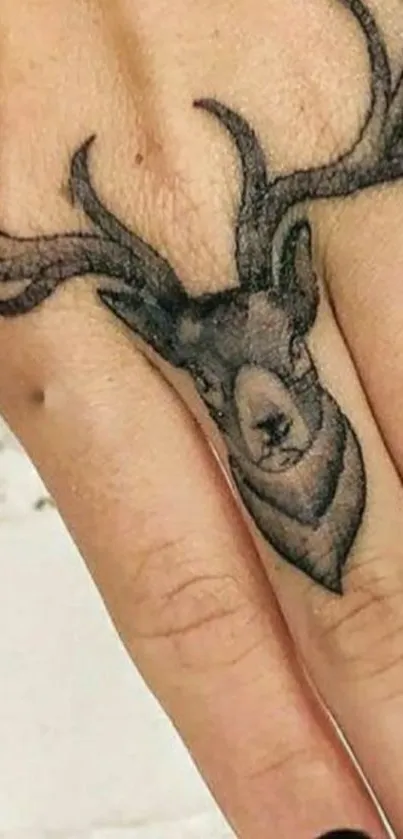 Hand with a tattoo of a deer head and antlers.