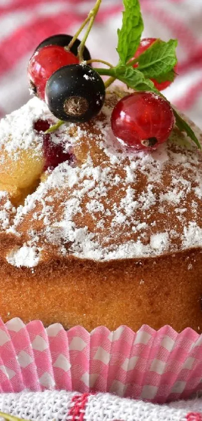 Muffin with powdered sugar and berries on a plaid cloth.