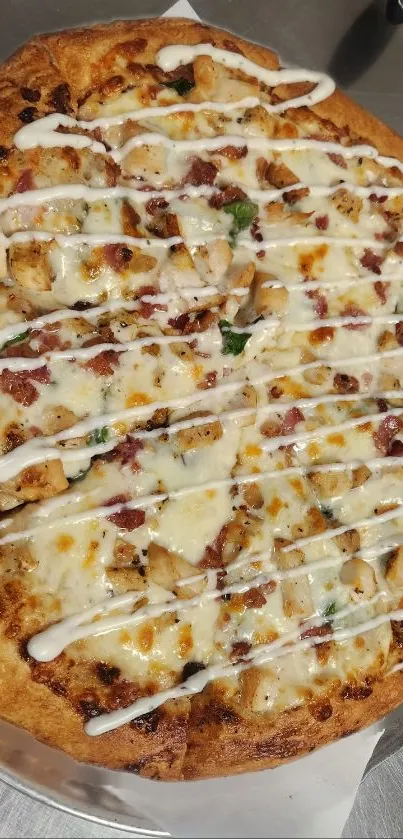 Golden brown chicken pizza with creamy drizzle topping.