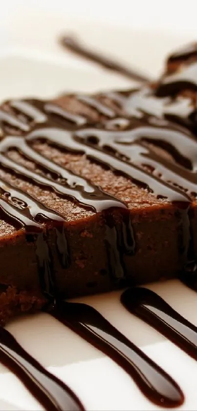 A rich chocolate brownie drizzled with syrup on a plate.