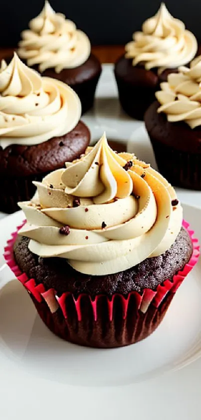 Chocolate cupcakes with creamy frosting on plates.