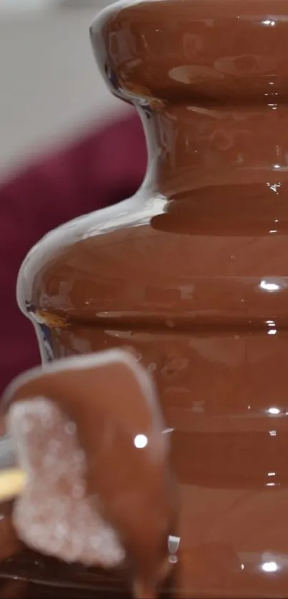 Rich chocolate fountain with marshmallow on skewer.