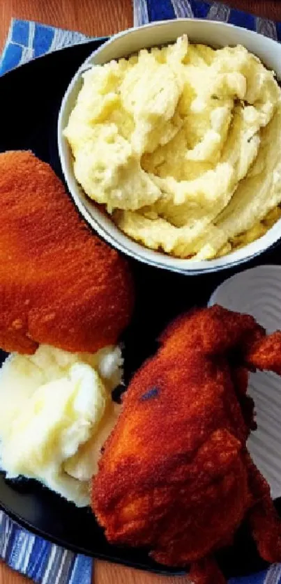 Crispy fried chicken served with mashed potatoes on a black plate.