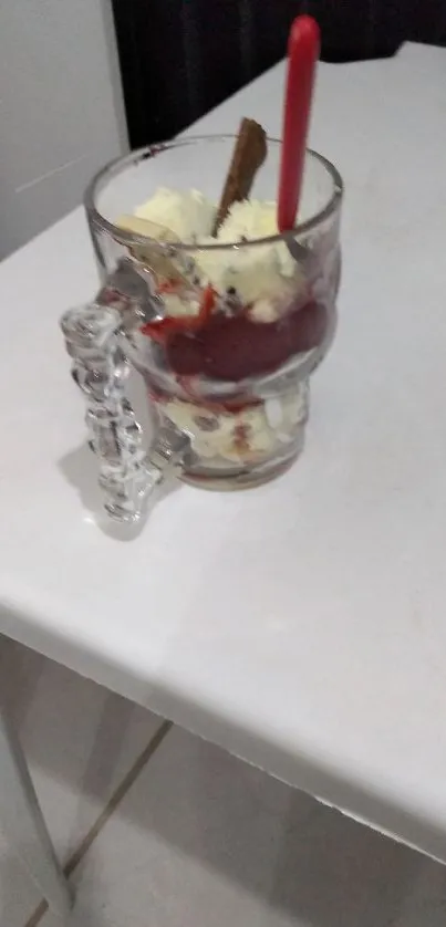 Glass mug filled with vanilla ice cream and strawberry sauce.