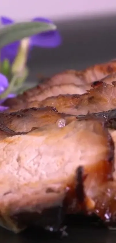 Close-up of grilled meat with purple flowers on a plate.