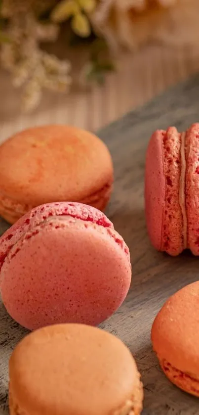 Mobile wallpaper featuring pink and orange macarons on wooden board.