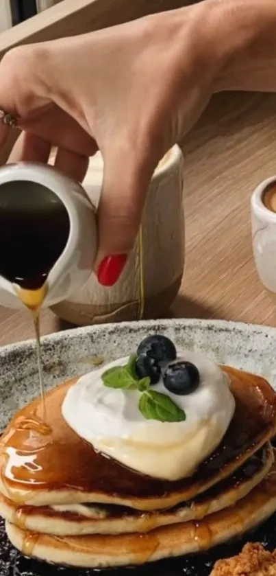 Pancakes topped with syrup and blueberries on a wooden table.