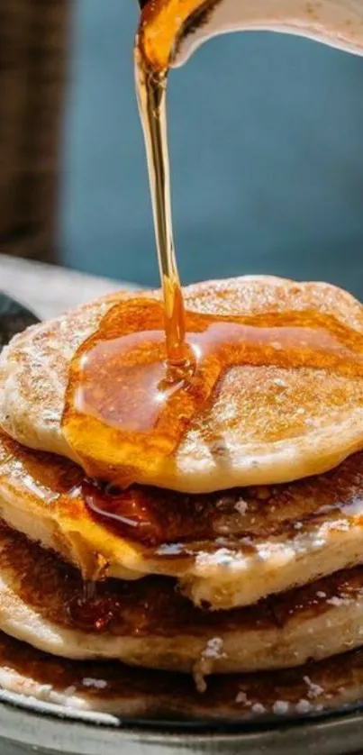 Stack of pancakes with syrup pouring over.