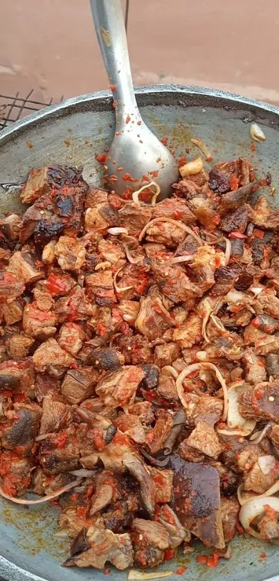 Spicy meat mix in a cooking pan with a metal spoon.