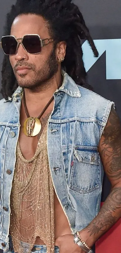 Person in denim vest and sunglasses with tattoos at VMA event.