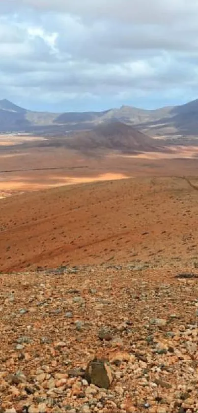 Vast desert landscape with distant mountains and a rocky foreground.