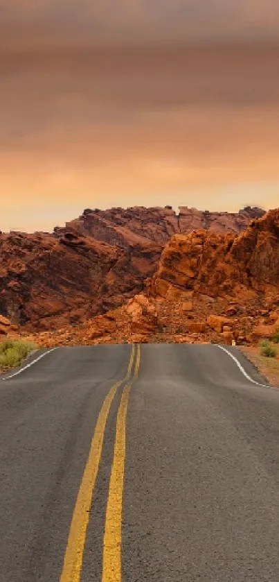 Scenic desert road at sunset with orange skies and rugged mountains.