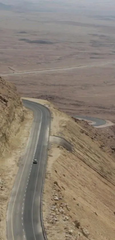 Winding road through vast desert landscape under clear sky.