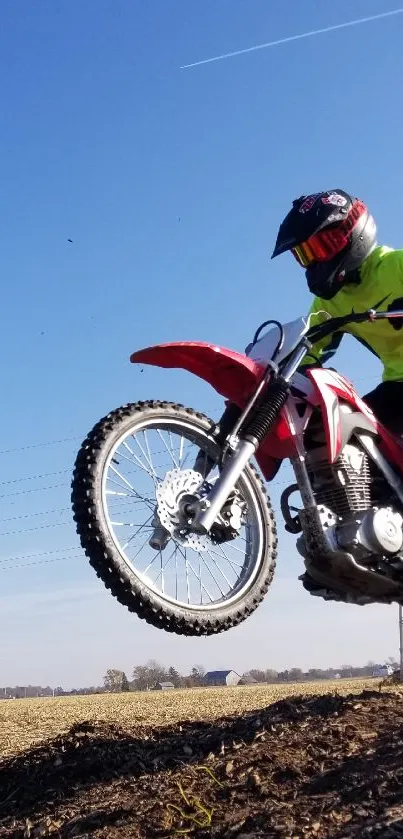 Motocross bike soaring through clear blue sky with a vibrant scenic backdrop.