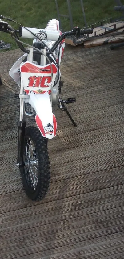 A dirt bike parked on a wooden deck outdoors.