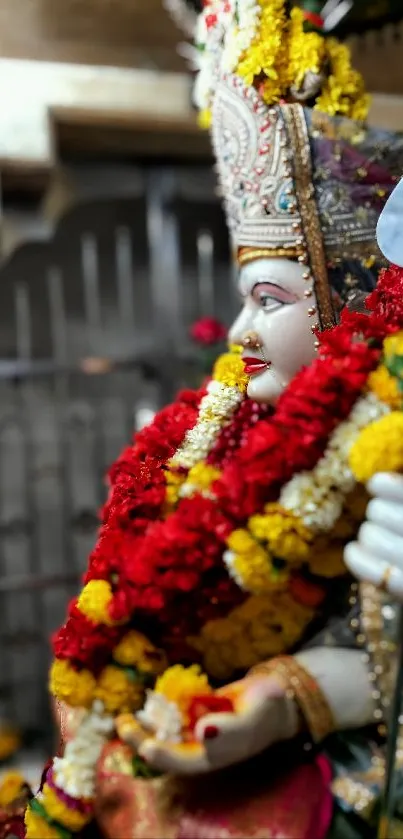 Deity statue adorned with vibrant colorful flowers.