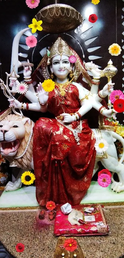 Goddess Durga with lion in vibrant red attire surrounded by flowers.