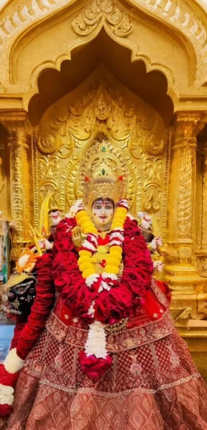 Golden temple deity adorned with flowers.