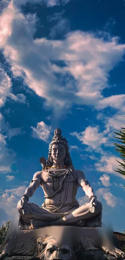 Statue of Lord Shiva against a blue sky with clouds, exuding serenity.