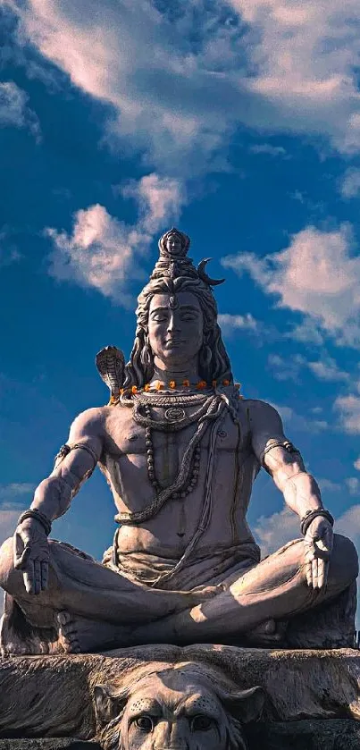 Shiva statue under a vibrant blue sky with clouds.