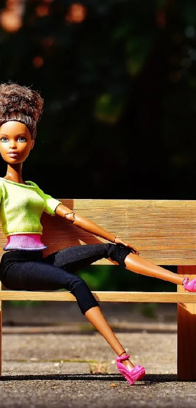 Doll sitting on a park bench with green shirt and pink shoes.