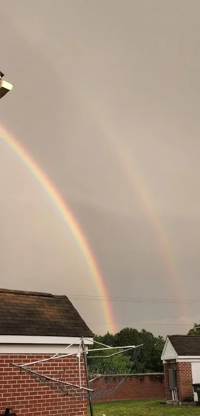 Mobile wallpaper of a double rainbow over suburban brick houses.