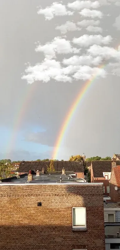 A stunning double rainbow over a suburban skyline under a gray sky.