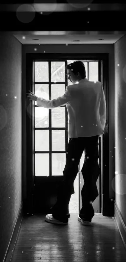 Silhouette in a dimly lit hallway with a windowed door ahead.