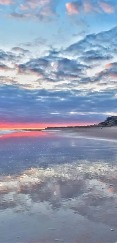 Sunset over a beach with a castle, reflecting a colorful sky in calm waters.