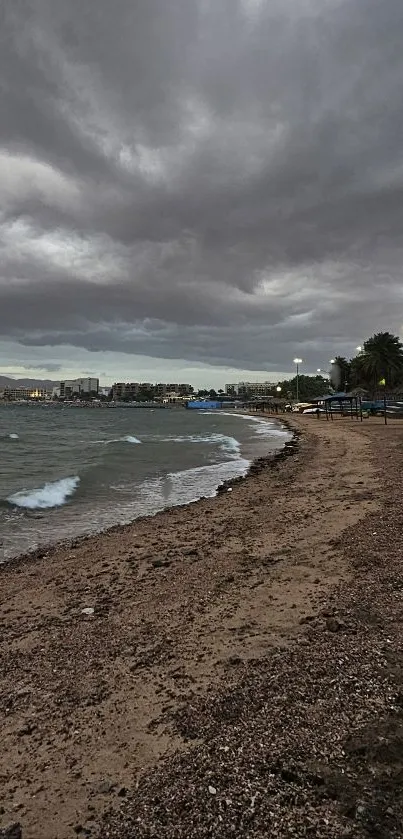 Moody beach under dramatic cloudy sky at dusk.