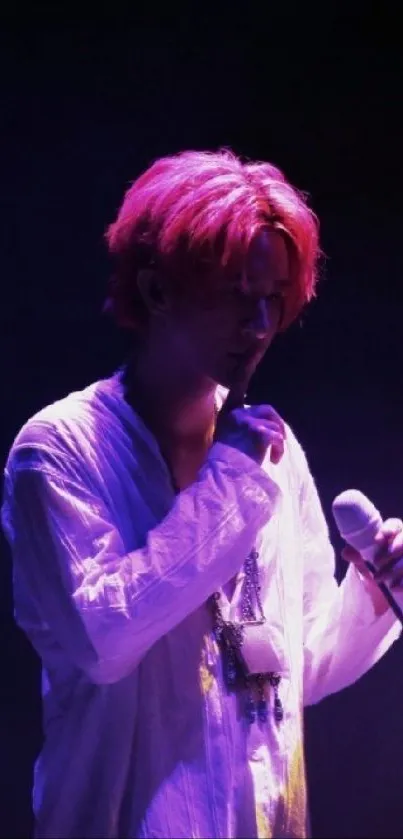 Singer with pink hair in spotlight at concert.