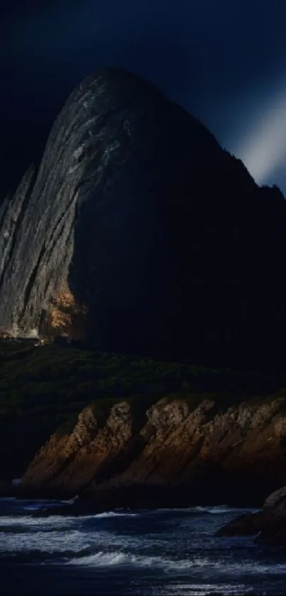 Dramatic mountain nightscape with rocky cliffs and dark blue sky.