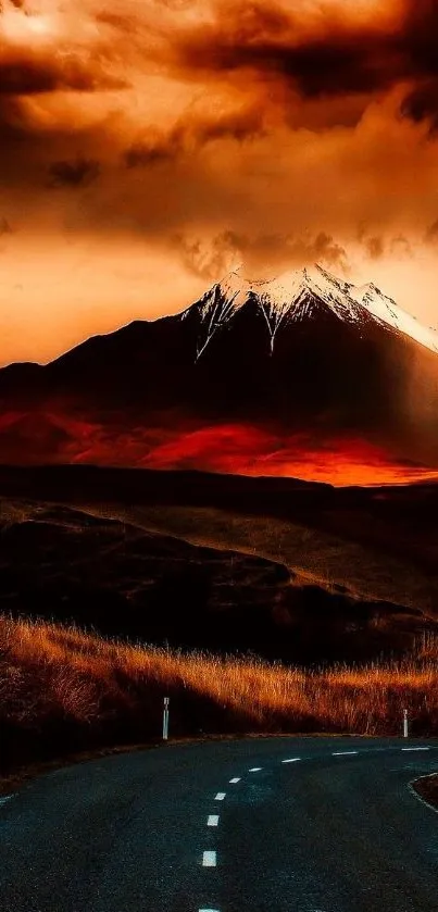 Road leading to snow-capped mountain under a dramatic orange sunset sky.