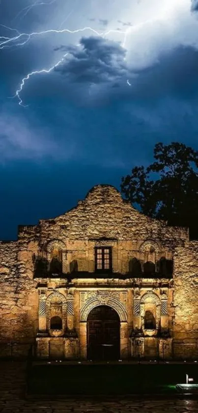 Historic building illuminated at night under a stormy sky.