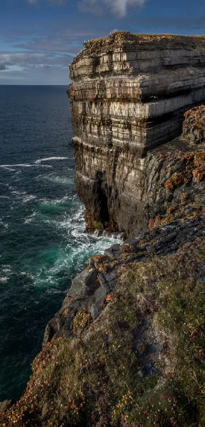 Cliff overlooking the ocean with vibrant sky and crashing waves.