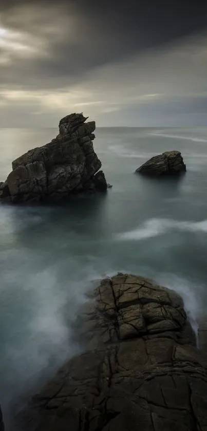 Dramatic rock formation over ocean under a moody sky at dusk.