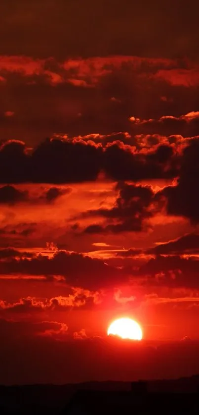 Dramatic red sunset with silhouetted clouds and skyline.