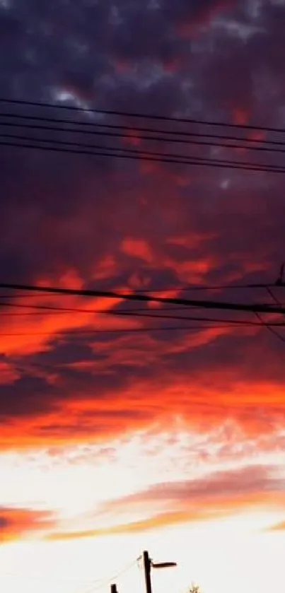 Dramatic sunset with orange and purple clouds over power lines.
