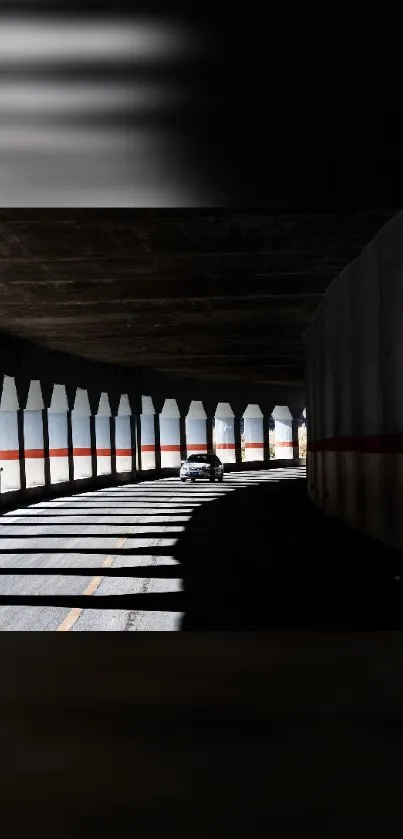 Car driving through shadowed urban tunnel with artistic light play.