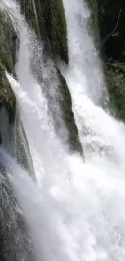 Dramatic waterfall with cascading water and lush greenery background.