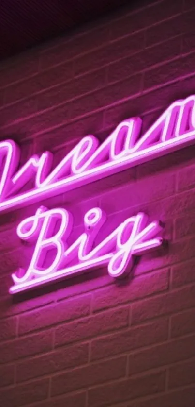 Neon pink 'Dream Big' sign on a brick wall.