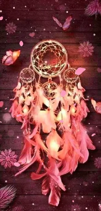 Dreamcatcher with pink feathers on a wooden background.